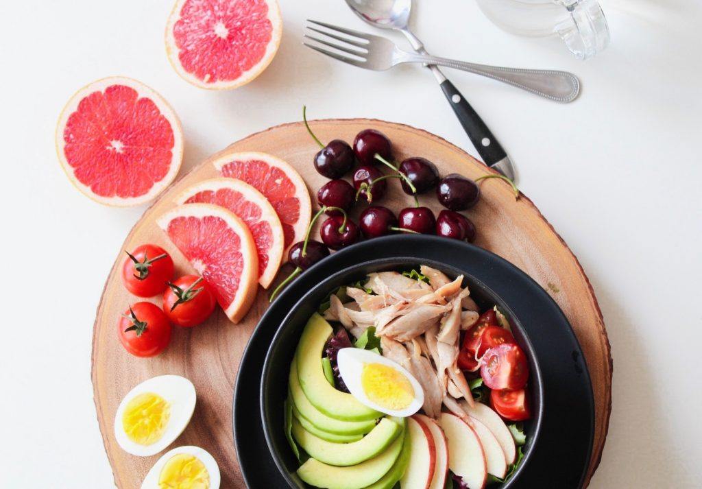 Preparing a dinner plate with tomatoes cherries grapefruit eggs avocado chicken apples and lettuce